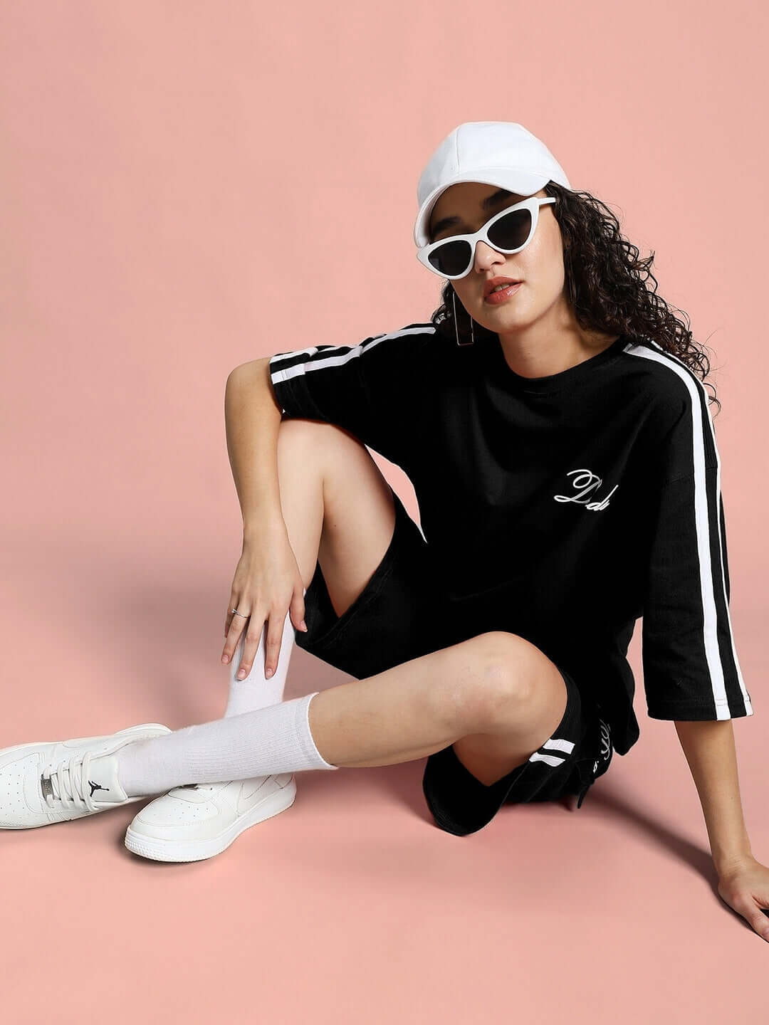 Model wearing WOMEN'S SCOTIA SUMMER CO-ORD SET BLACK with white cap and sunglasses, casual summer fashion.
