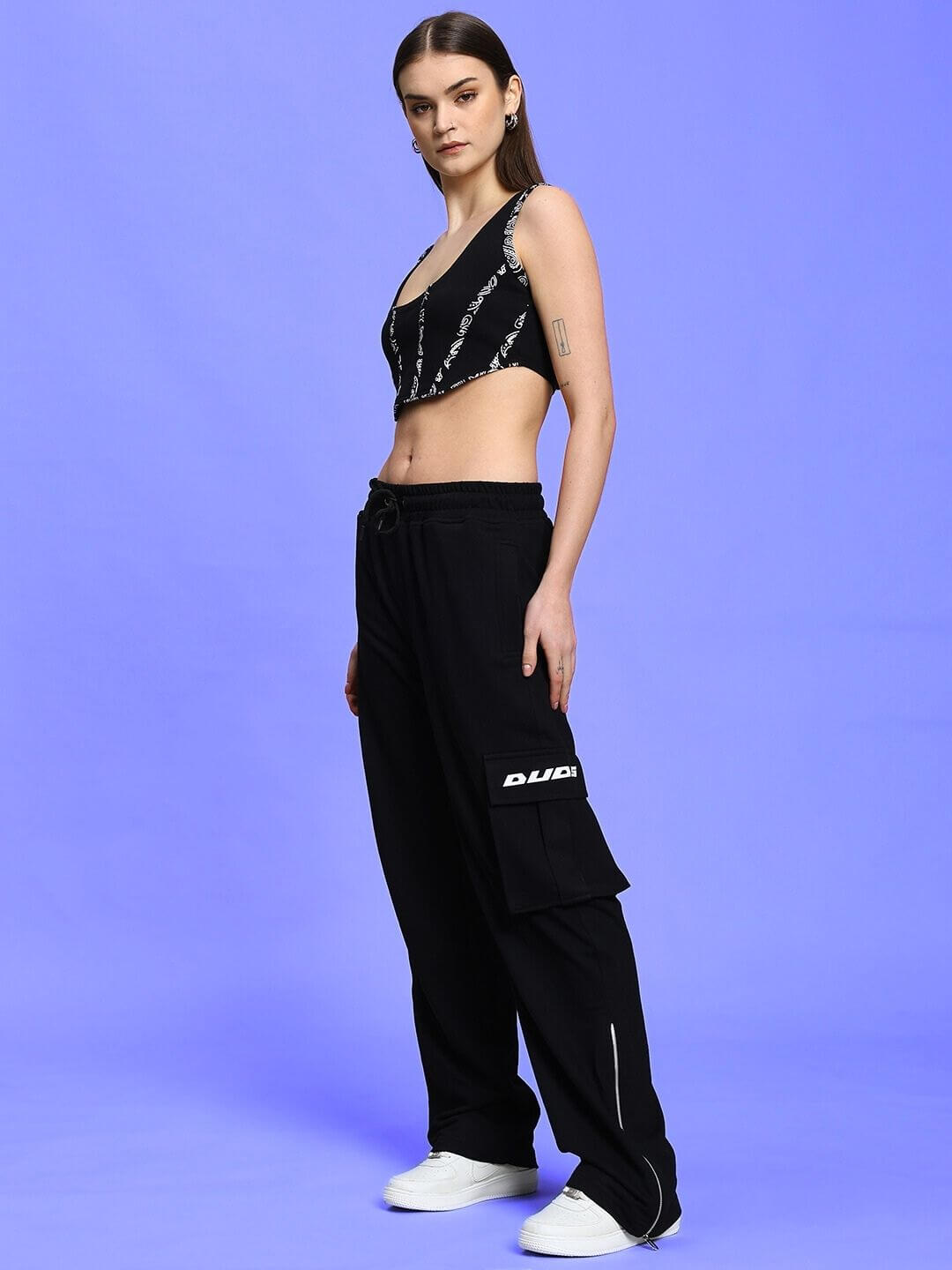 Model wearing Women's Skidder Cargo Pant in black, featuring side pocket and logo detail, made by DUDS, available for custom fit orders.