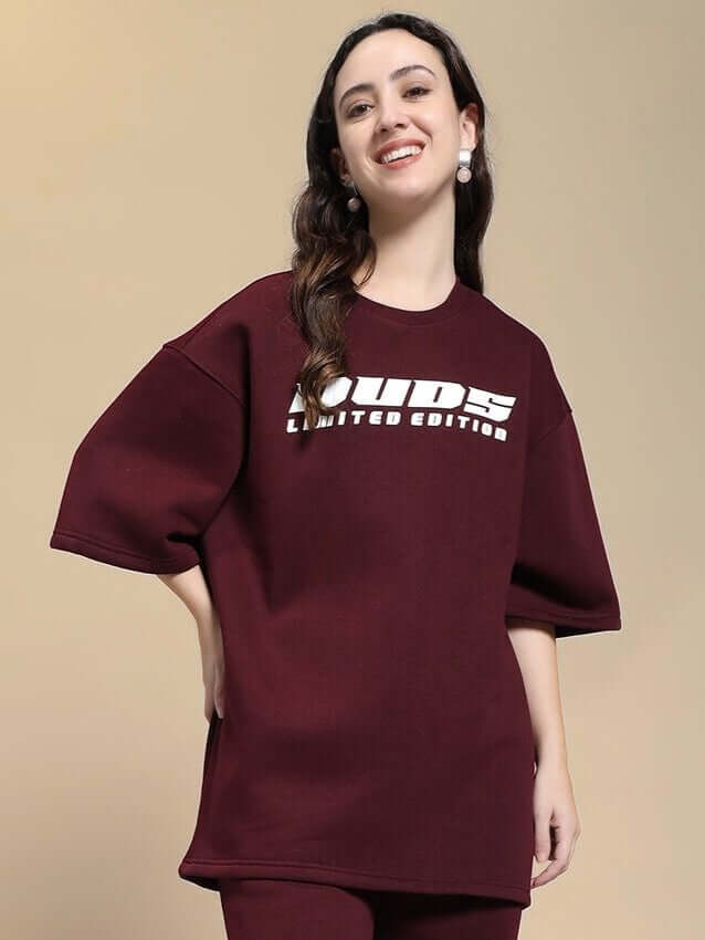 Woman wearing a WOMEN SKODA FLEECE OVERSIZED T-SHIRT MAROON smiling, showcasing cozy-chic and modern style with a deep maroon color.