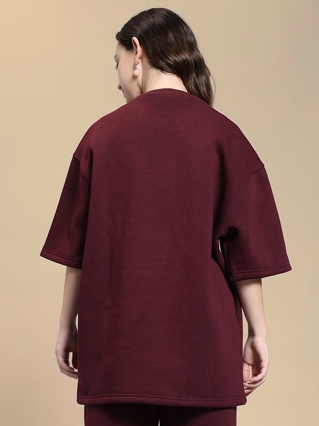 Back view of a woman wearing WOMEN'S SKODA FLEECE OVERSIZED T-SHIRT MAROON in a casual setting.