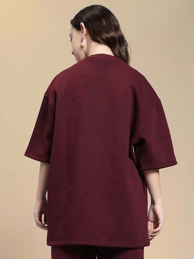 Back view of WOMEN SKODA FLEECE OVERSIZED T-SHIRT MAROON showcasing the deep maroon color on a model, highlighting cozy-chic style.