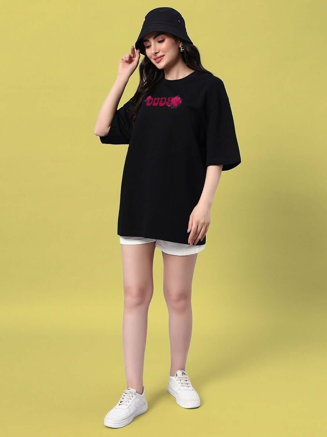 Model wearing women's black oversized t-shirt with skull roses design, paired with white shorts and sneakers, ideal for summer.