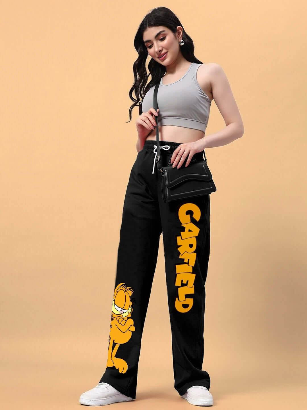 Woman wearing black Garfield relaxed fit joggers paired with a gray crop top and carrying a black purse.