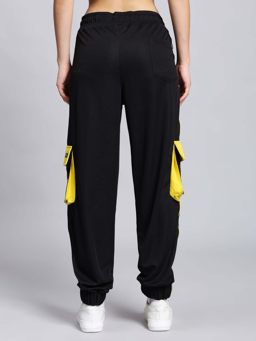Back view of Women's Soccer Regular Fit Cargo Jogger in black with yellow pockets, showcasing casual style.