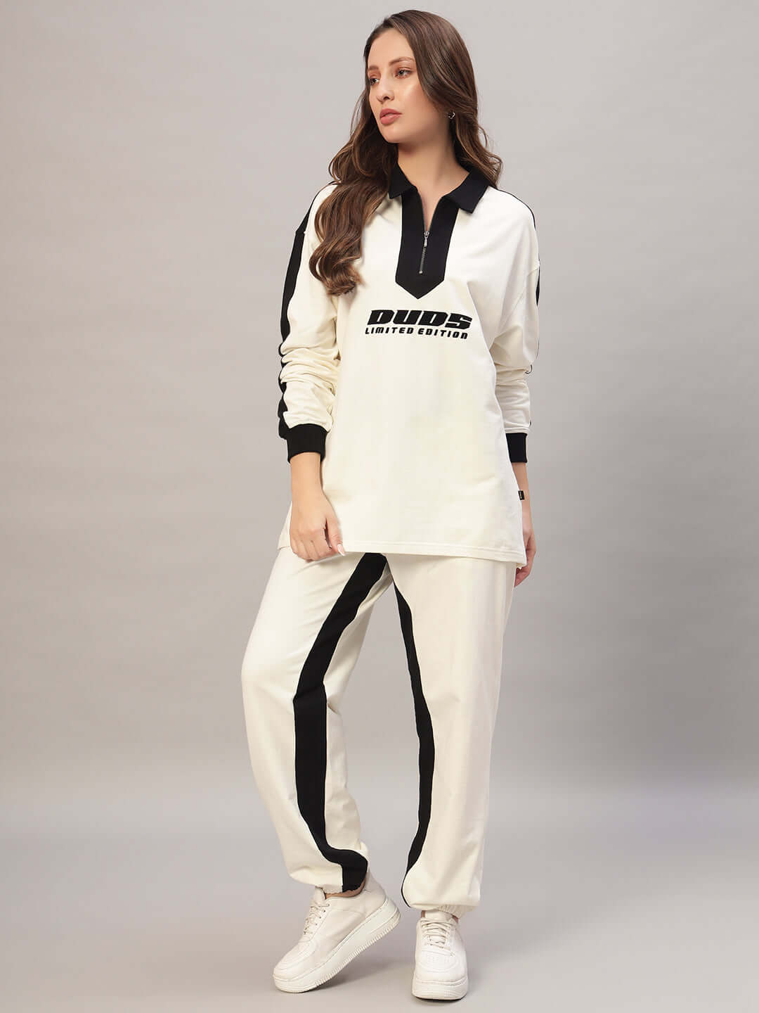 Woman wearing a stylish WOMEN SPLINTER OVERSIZED CO-ORD SET OFF WHITE BLACK featuring an oversized sweatshirt and joggers.