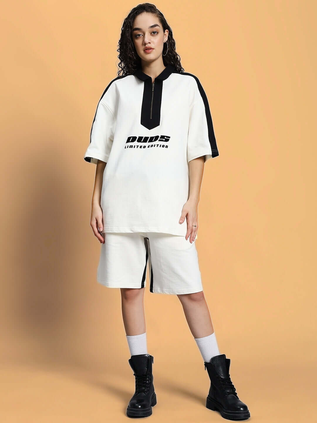Model wearing WOMEN SPLINTER SUMMER CO-ORD SET OFF WHITE with black accents and boots, showcasing modern minimalism in a stylish design.