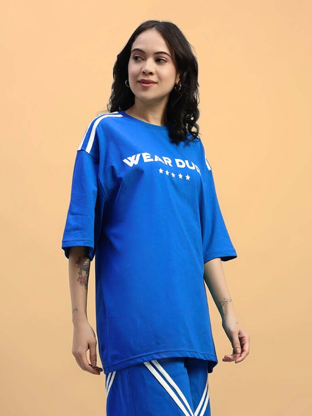 Woman wearing a blue oversized t-shirt with star design, made from premium cotton fabric, featuring sporty stripes.