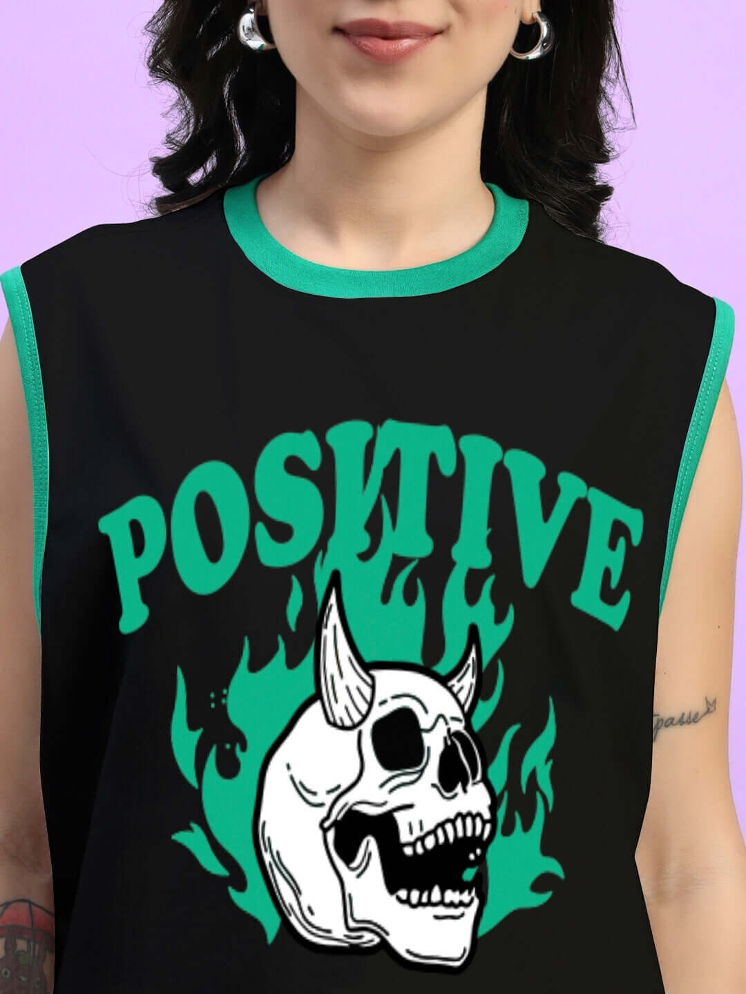 Woman wearing a black oversized t-shirt with a green 'Stay Positive' skull design, ideal for a trendy summer look.