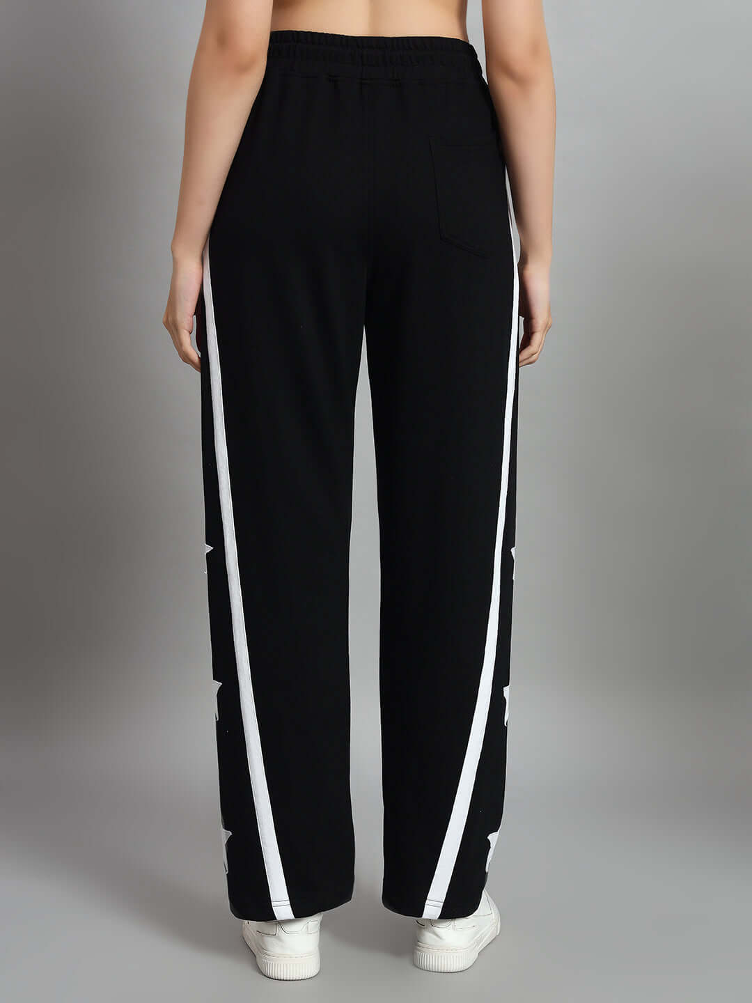 Back view of women's black joggers with white side stripes, featuring relaxed fit, perfect for casual wear.