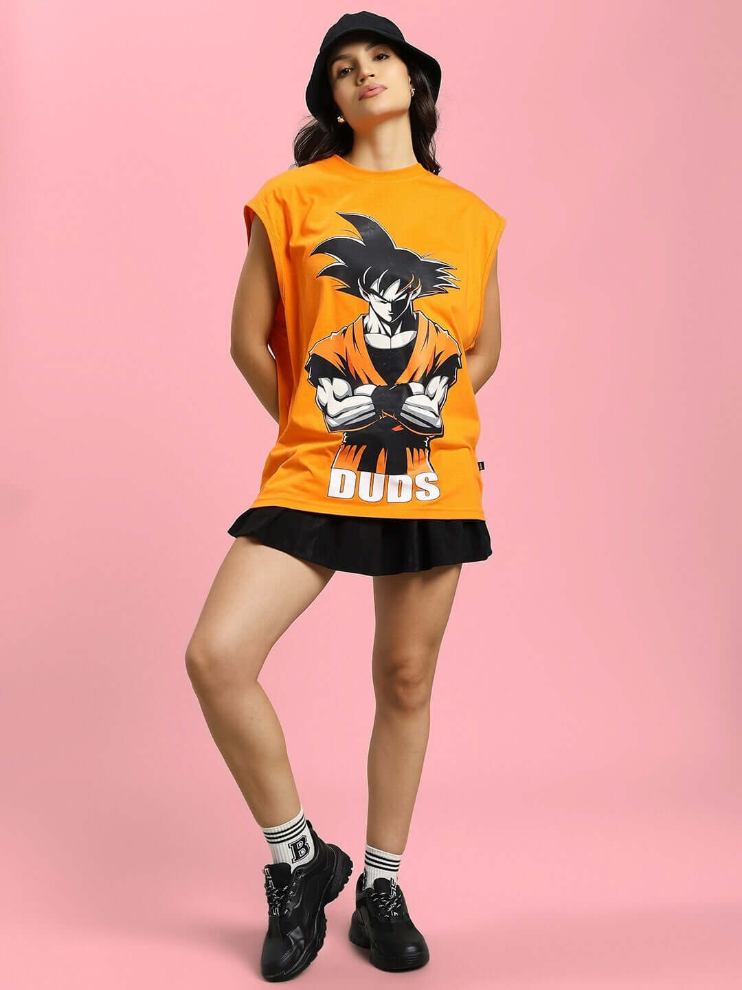 Woman wearing orange Super Saiyan gym t-shirt by DUDS with anime design, standing against pink background, perfect for custom fit.