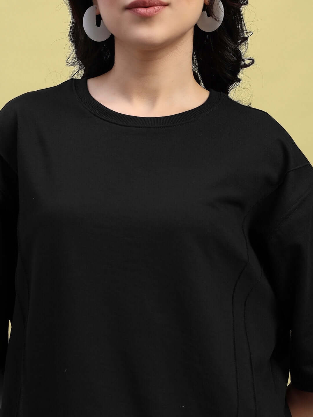 Close-up of a woman's black oversized t-shirt made from premium cotton fabric, showcasing the superior fabric quality and relaxed fit.