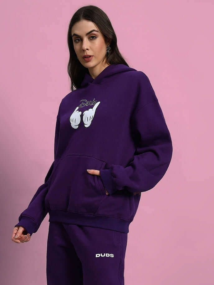 Woman wearing WOMEN SUPREME FLEECE HOODIE PURPLE against pink background