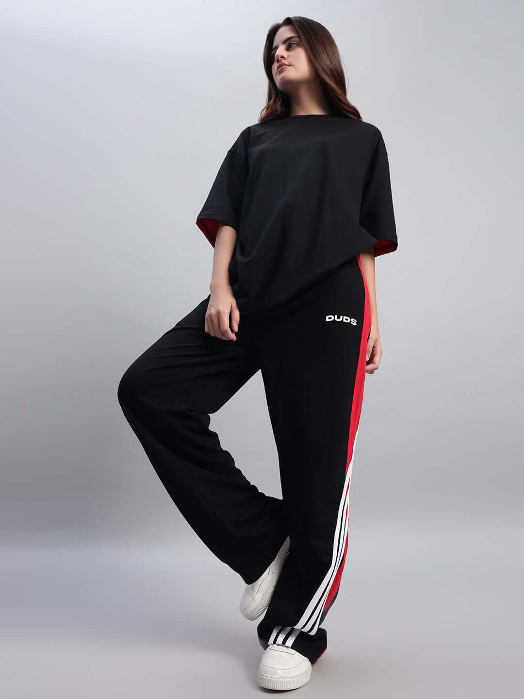 Woman wearing DUDS Women's Tangle Relaxed-Fit Joggers in Black-Red with white sneakers, showcasing casual style fashion.