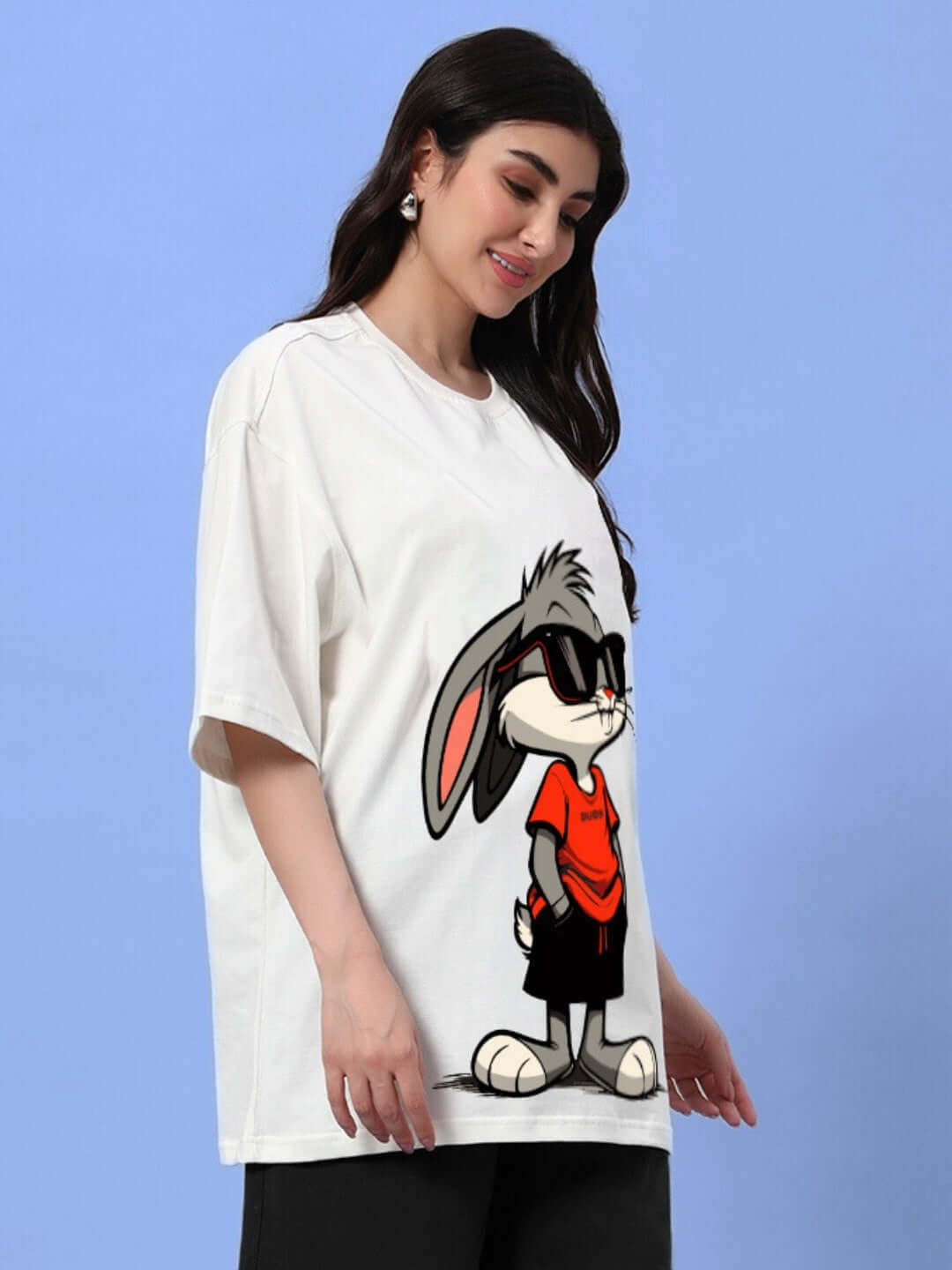 Woman wearing oversized off-white T-shirt featuring a cartoon bunny with sunglasses, perfect for a casual summer look.