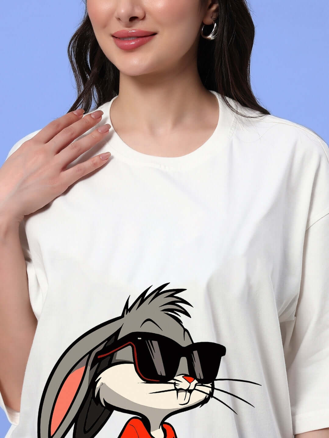 Woman wearing oversized off-white t-shirt featuring a cartoon bunny with sunglasses, ideal for a trendy summer look.