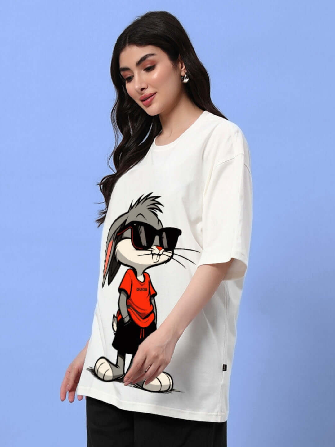Woman wearing an oversized off-white t-shirt with a cartoon bunny design, perfect for a trendy and comfortable summer look.