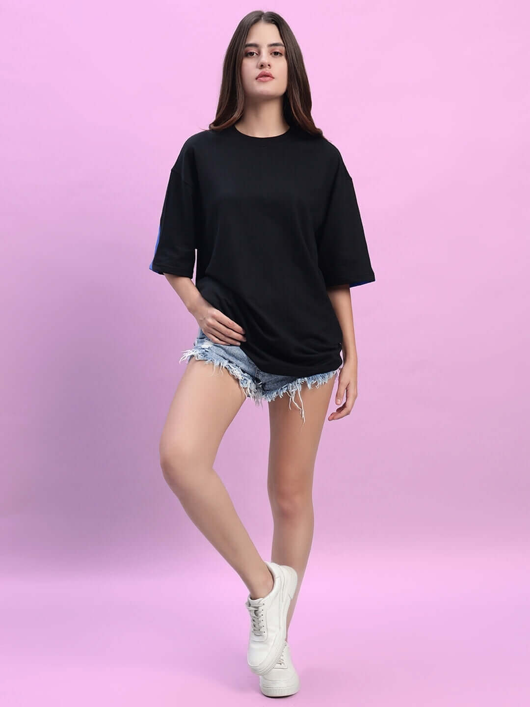 Model wearing women's Titan oversized T-shirt in black-blue, made from premium heavy gauge fabric, displayed on pink background.
