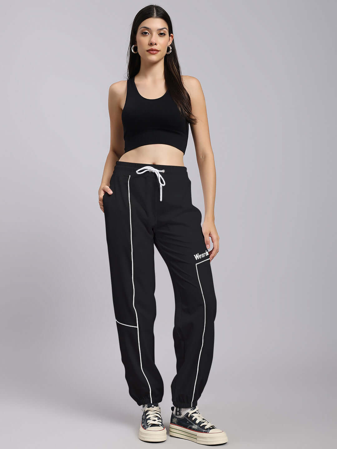 Model wearing Women's Tokyo Relaxed Fit Joggers in Black, featuring custom fit option by DUDS, paired with black tank top and sneakers.