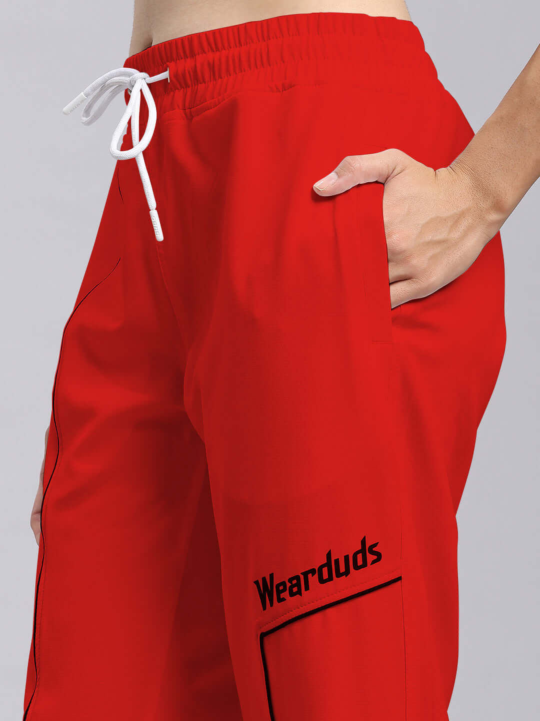 Close-up of red women's relaxed fit joggers from DUDS with drawstring waist and branded pocket, showcasing modern design and comfort.