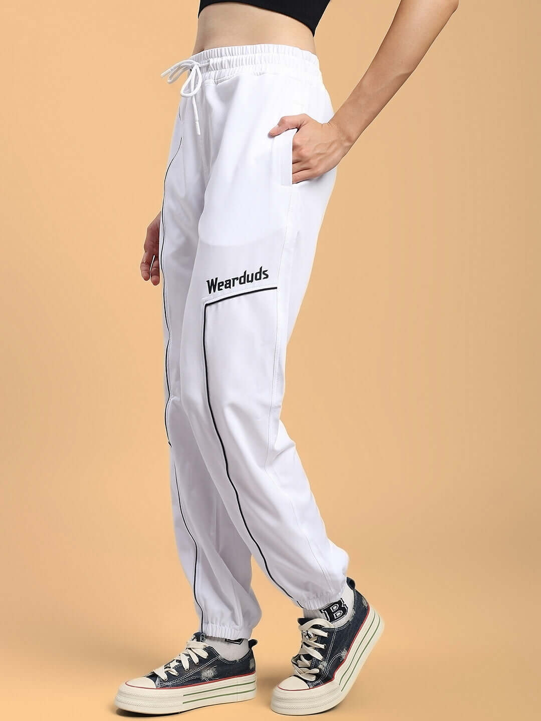 Woman wearing WOMENS TOKYO RELAXED FIT JOGGERS WHITE with sneakers, showcasing modern style and comfort.