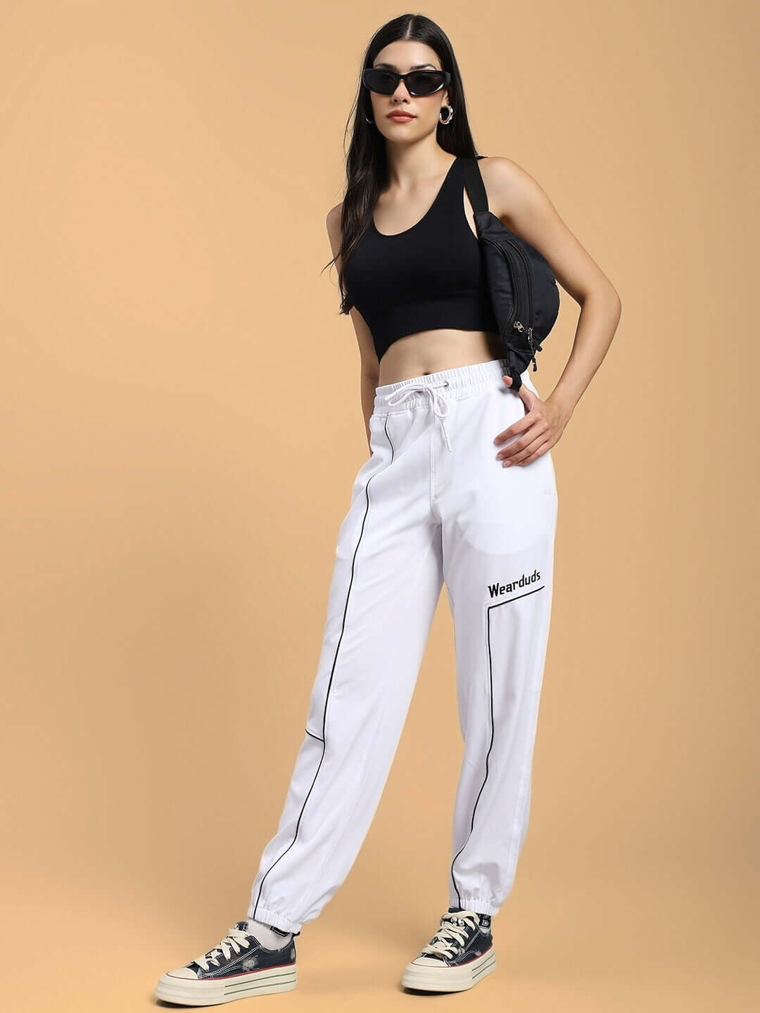 Woman wearing WOMENS TOKYO RELAXED FIT JOGGERS WHITE, pairing with a black top and sneakers.