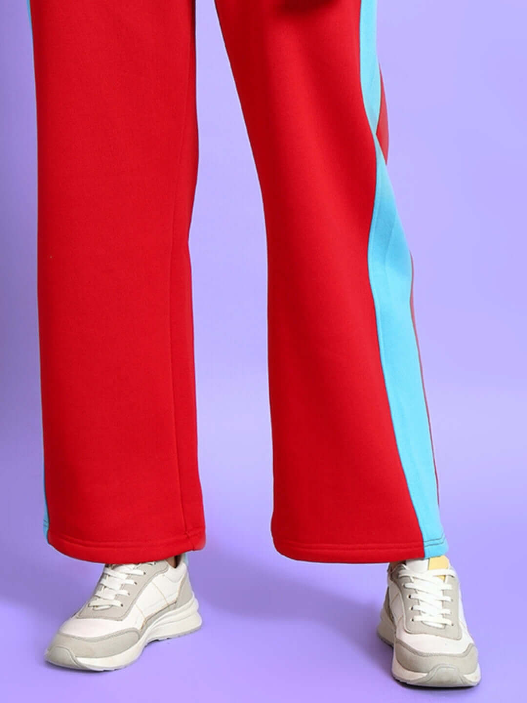 WOMEN TRUNKIT FLEECE COLORBLOCK CARGO PANT in vibrant red and blue with white sneakers on a purple background.