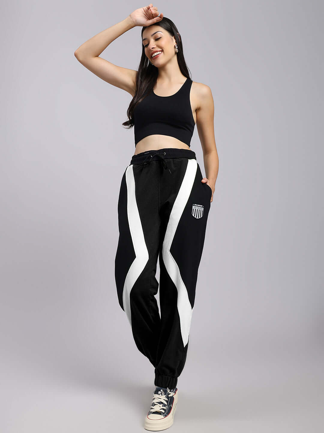 Woman wearing black and white colorblock joggers, smiling and posing confidently against a neutral background.