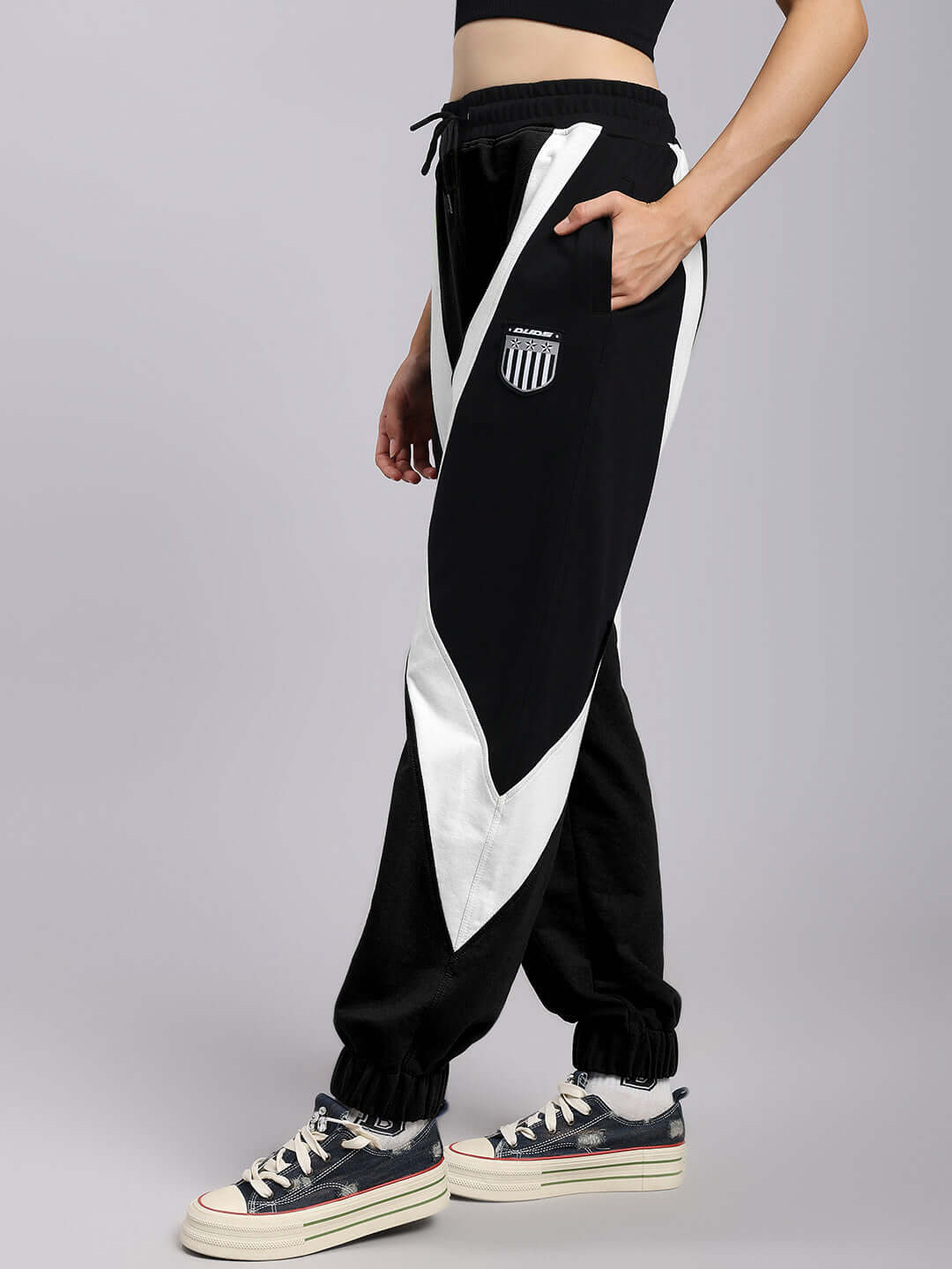 Model wearing women's black and white ultra colorblock relaxed-fit joggers by DUDS, shown with sneakers for a casual look.