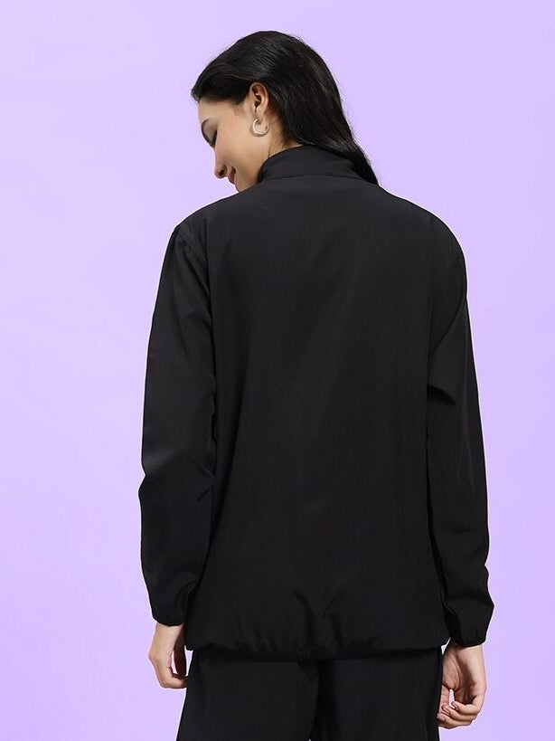 Back view of WOMEN UNISON RELAXED FIT JACKET BLACK RED in black, showcasing a relaxed fit on a purple background.