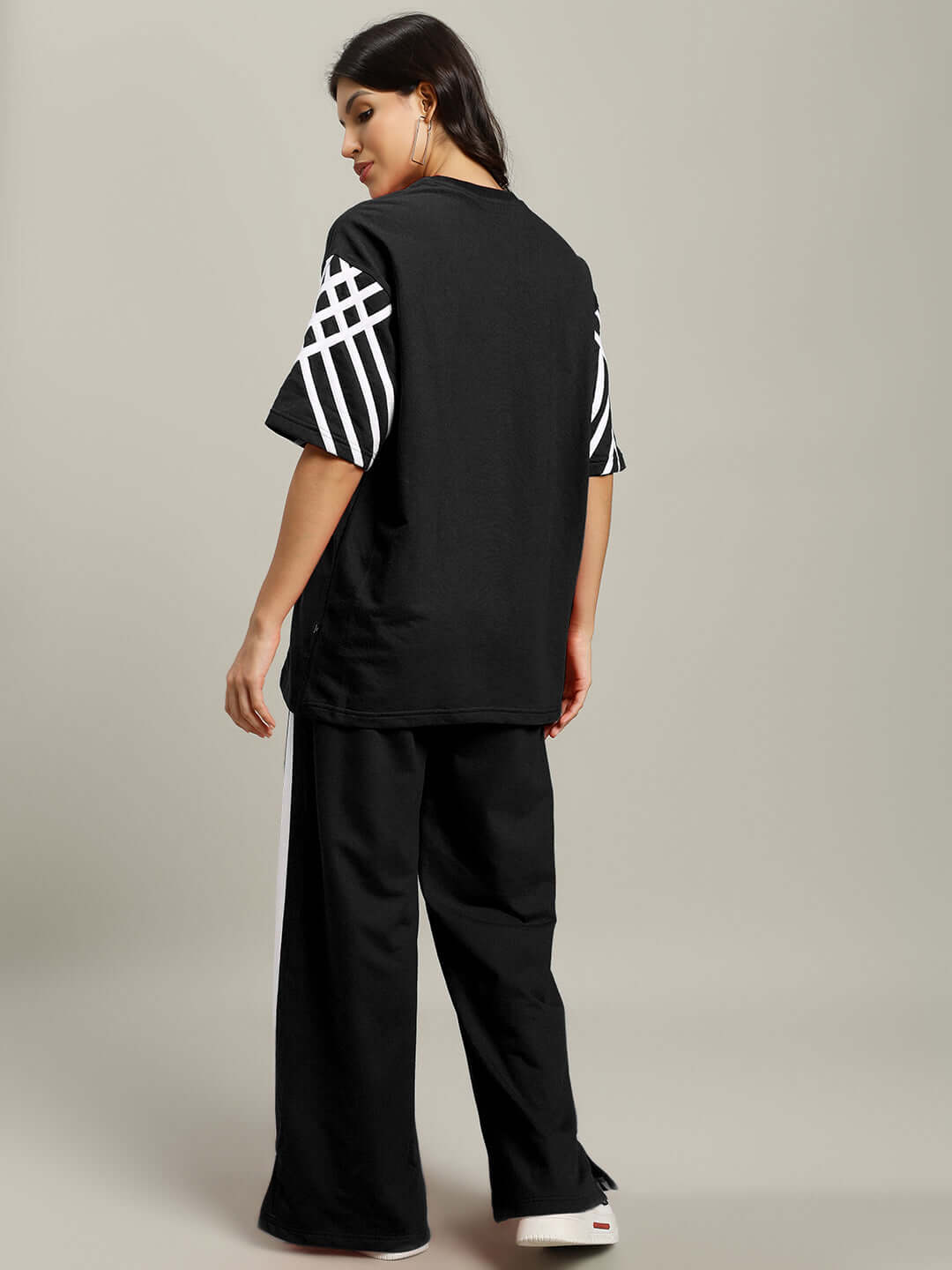 Model wearing Women's United Stripe Co-ord Set in Black with white striped sleeves, made from premium cotton French terry, viewed from the back.