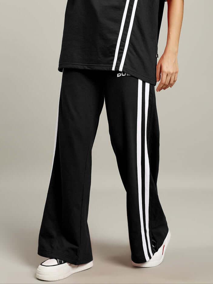 Black women's joggers with white stripes by DUDS, shown with a casual t-shirt and sneakers.