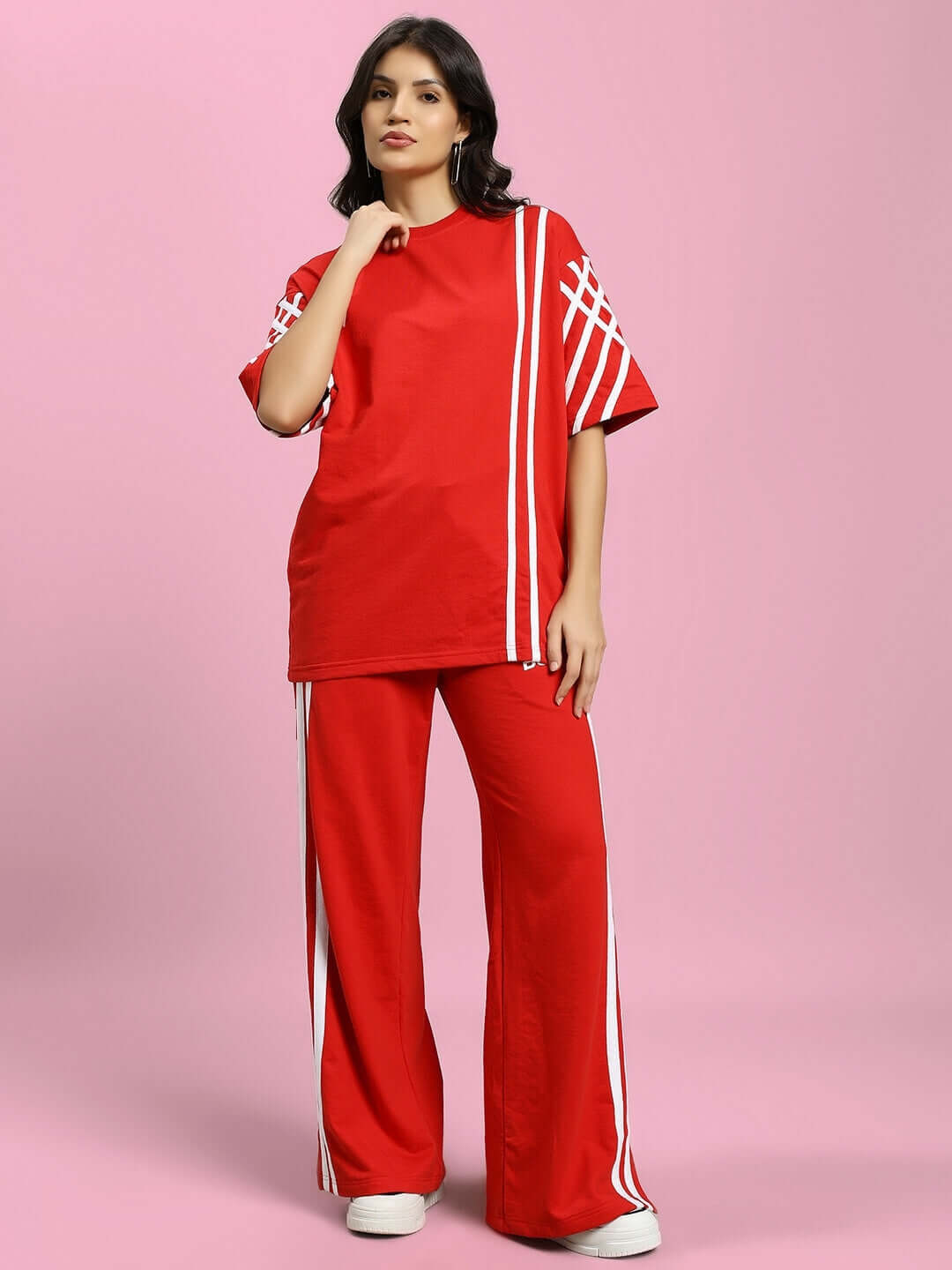 Model wearing red women's joggers with white stripes, made by DUDS, available in custom sizes. Stylish and comfortable casual wear.