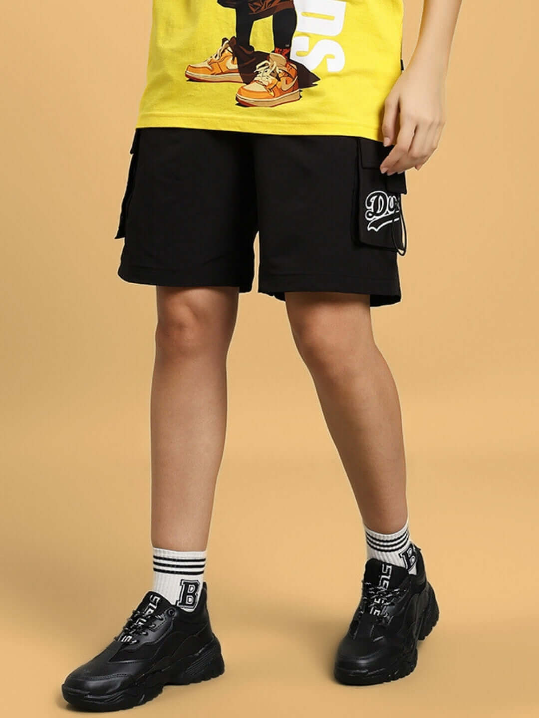 Women's Vega Cargo Shorts in Black featuring pockets, styled with black sneakers and a yellow top, perfect for casual outings.