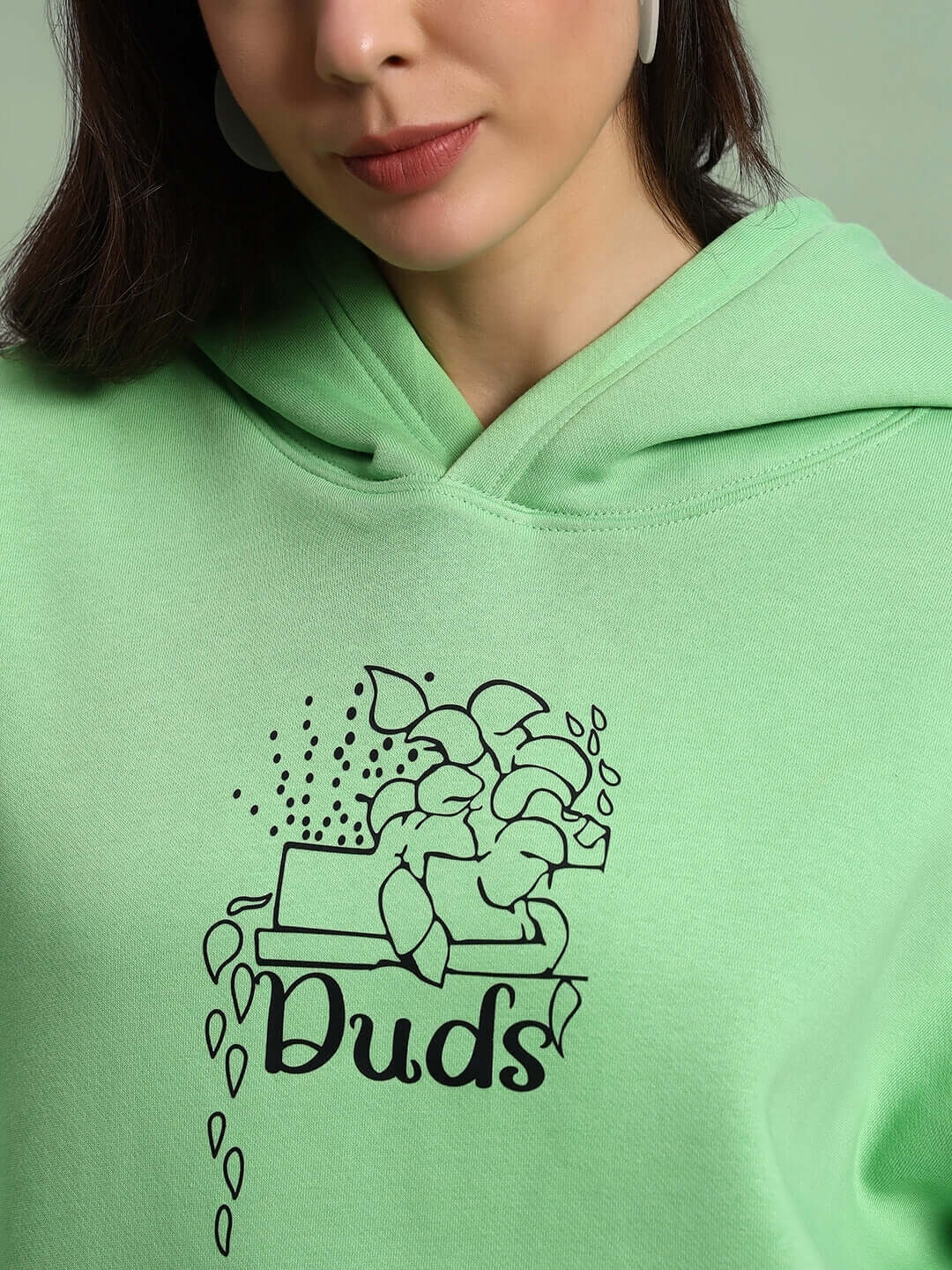 Close-up of WOMEN VOODO FLEECE OVERSIZED HOODIE GREEN with artistic logo design.