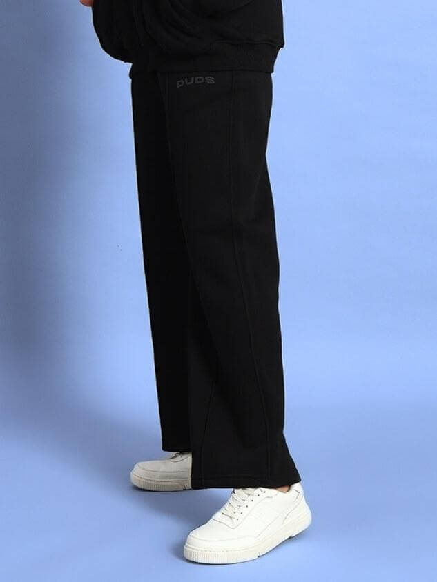 Women's stylish black fleece cargo pants by DUDS with white sneakers on blue background