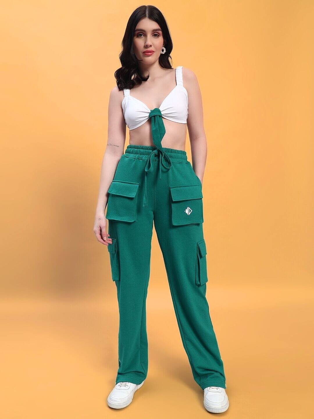 Woman wearing WOMEN'S EASTON CO-ORD SET WHITE-GREEN with white top and green cargo pants on orange background, showcasing casual style.