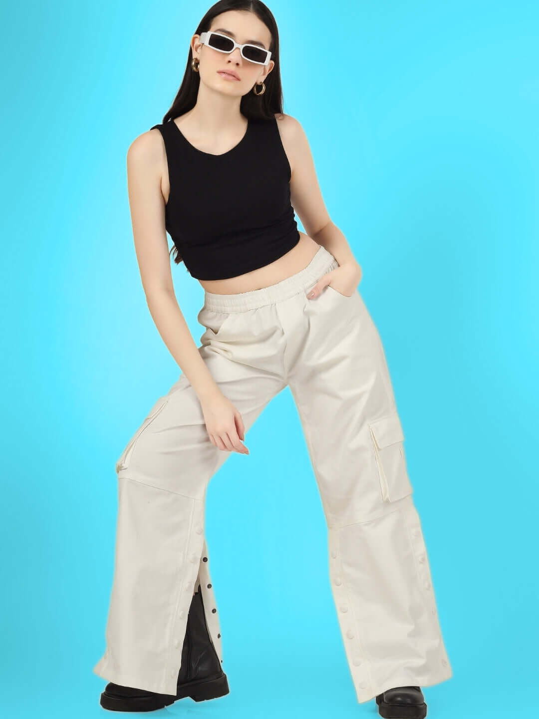 Model wearing women's side slit button cargo pants in white with black crop top, showcasing trendy fashion on a blue background.
