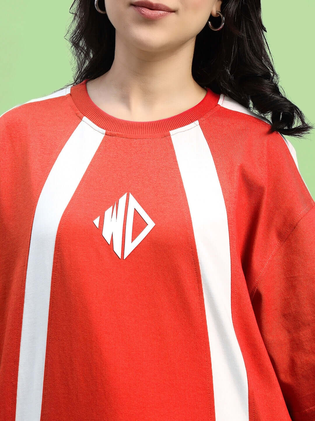 Women's red oversized T-shirt with white stripes, made from premium heavy gauge cotton fabric, displayed against a green background.