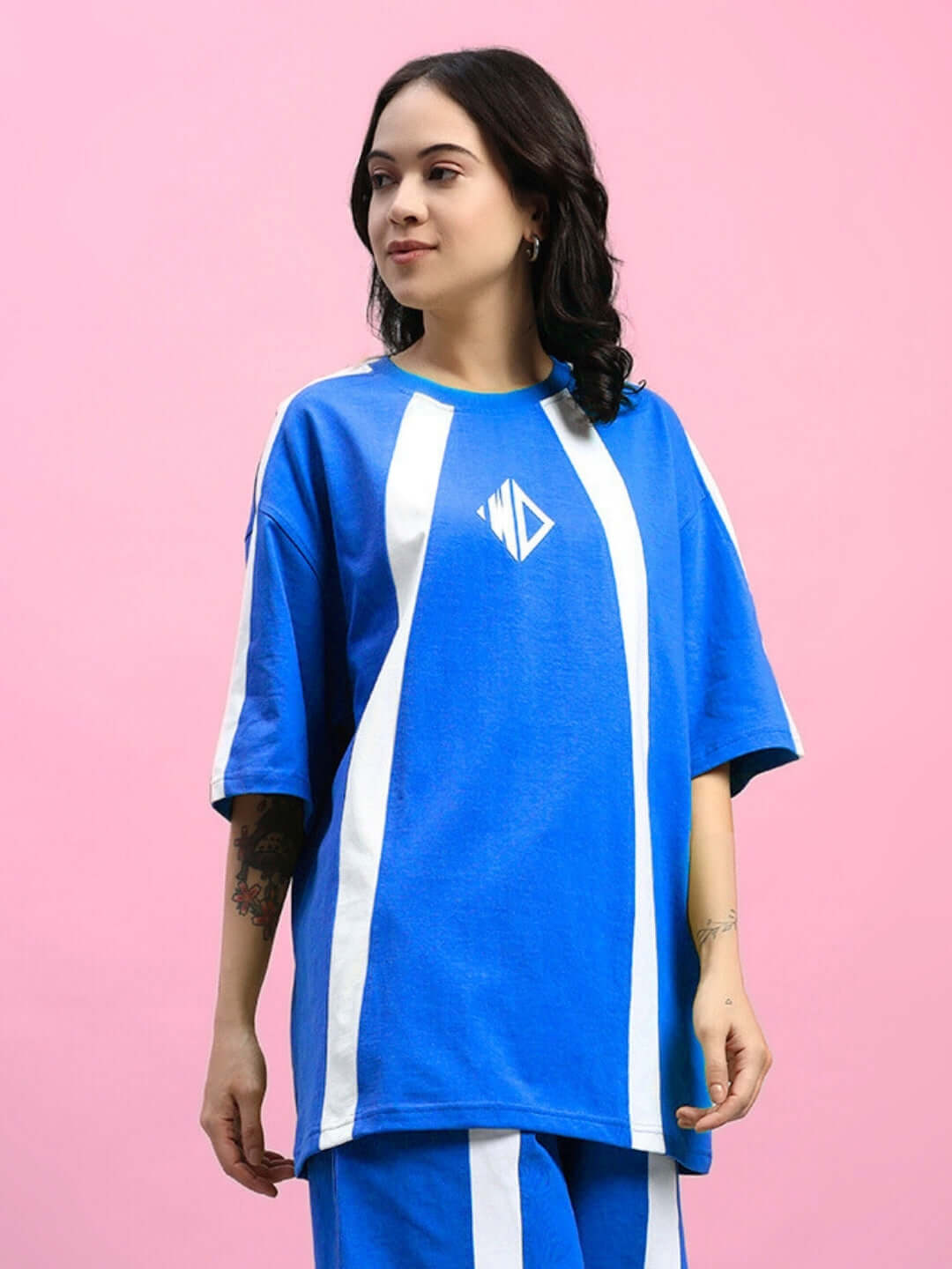 Woman wearing WOMENS WIDELINE OVER-SIZED T-SHIRT BLUE with trendy and relaxed fit against pink background.