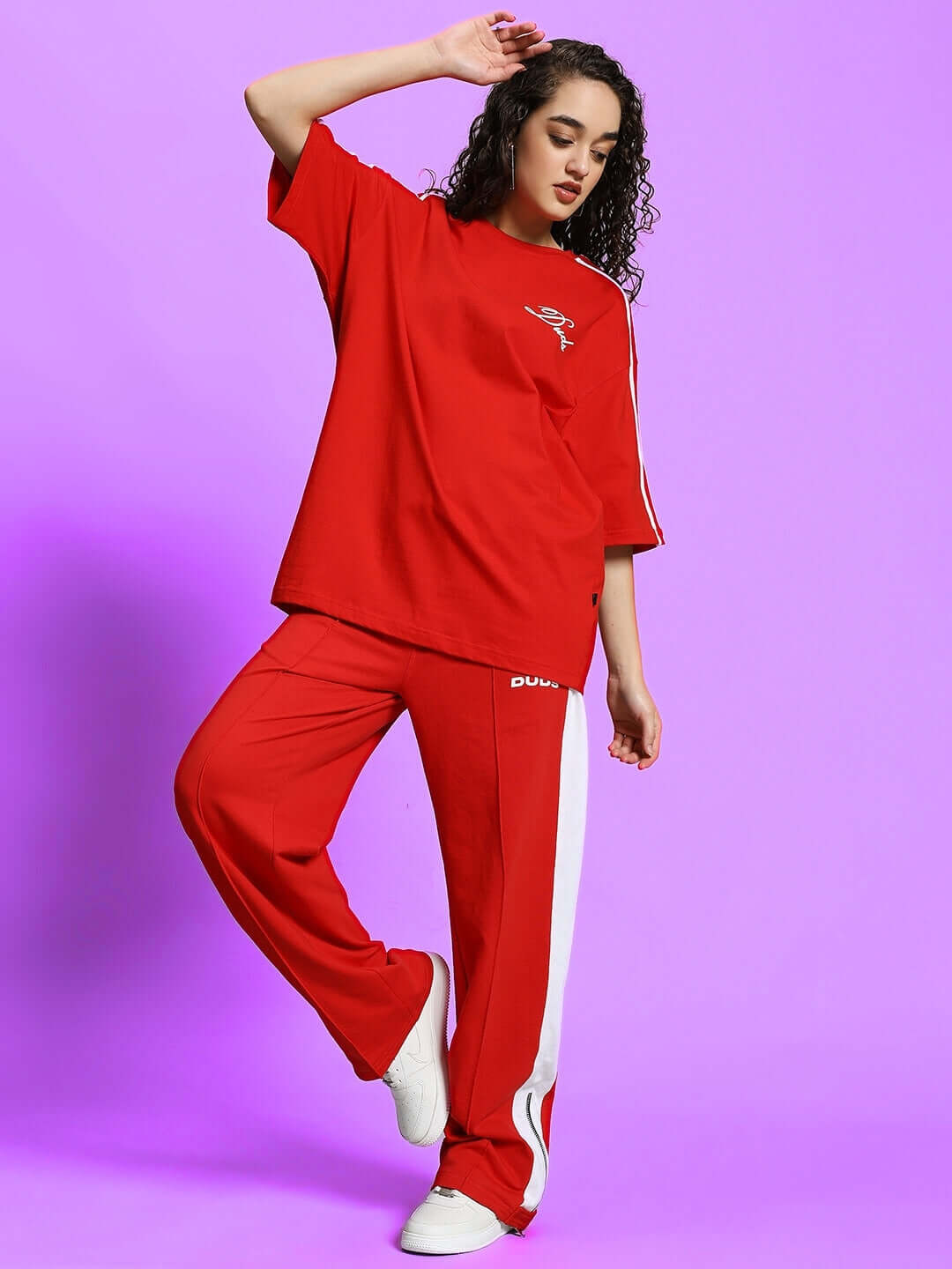 Alt Tag: Model wearing red-white Women's Wonder Slit Zipper Joggers by DUDS, styled for comfort and fashion on a purple background.