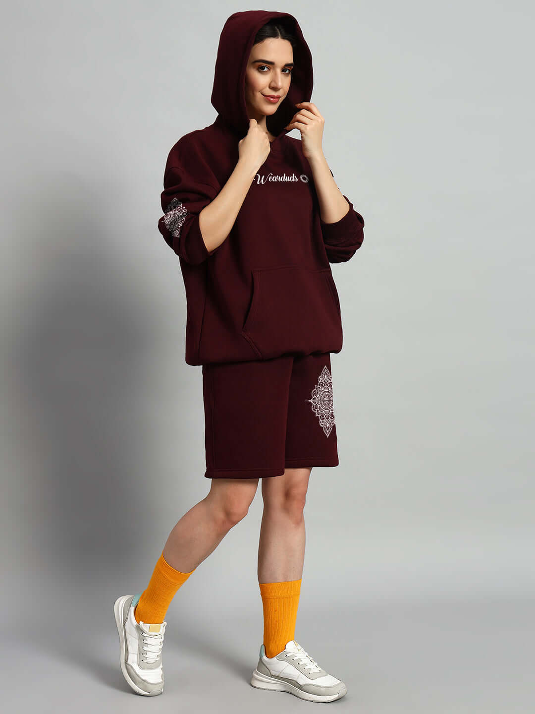 Model wearing WOMEN'S YANTRA FLEECE CO-ORD SET WINE, a stylish maroon outfit with yellow socks and sneakers, perfect for casual outings.