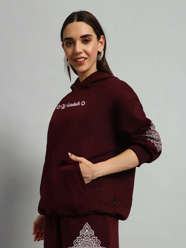 Woman wearing WOMENS YANTRA FLEECE HOODIE WINE with mandala design, showing comfort and style in rich wine color.