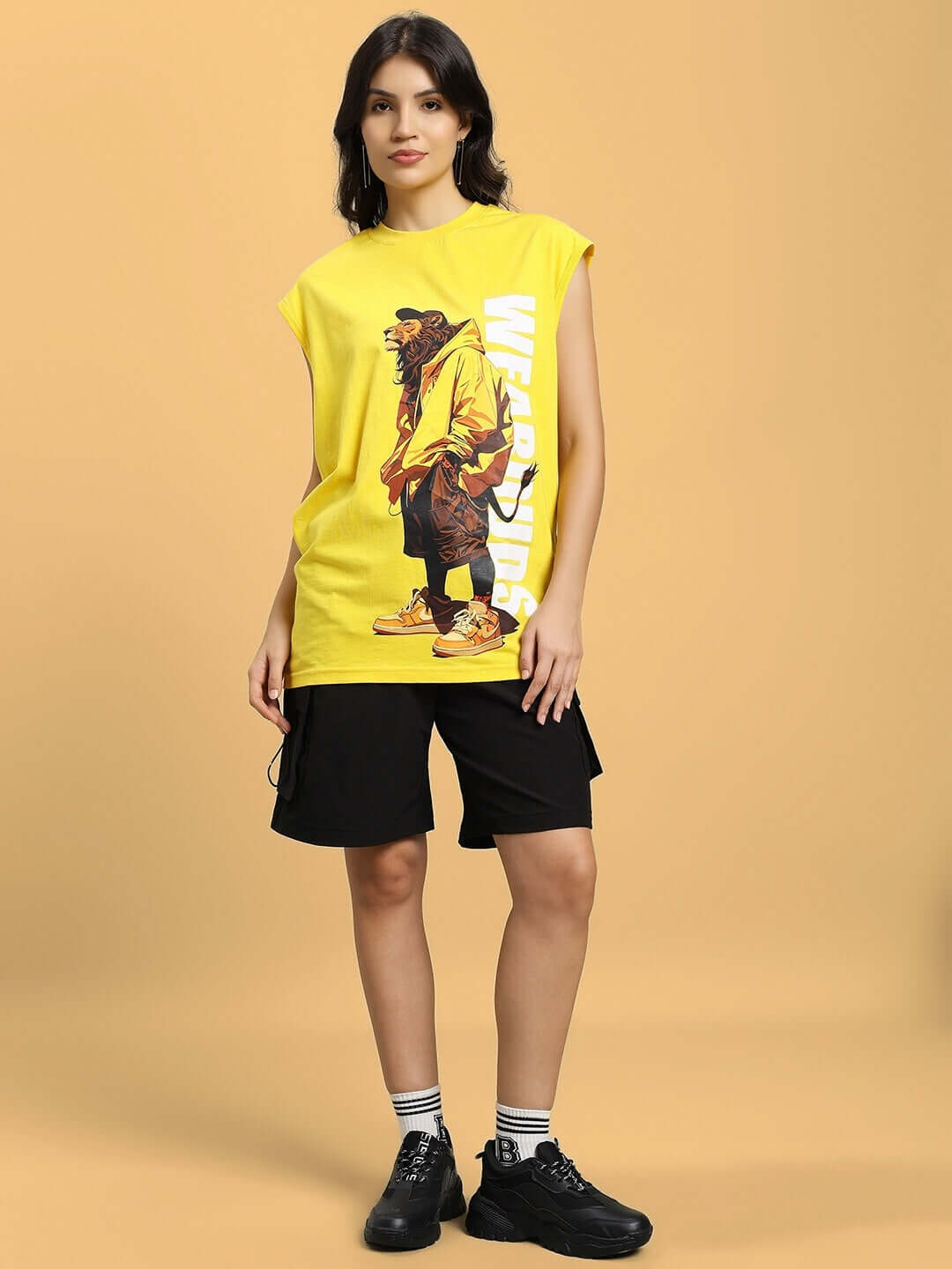 Woman wearing black cargo shorts with a yellow graphic t-shirt, standing on a neutral background.