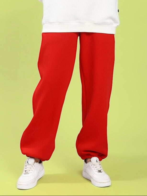 Model wearing WOMEN'S ZENO RELAXED FIT FLEECE JOGGER RED with white sneakers, showcasing comfort and style.