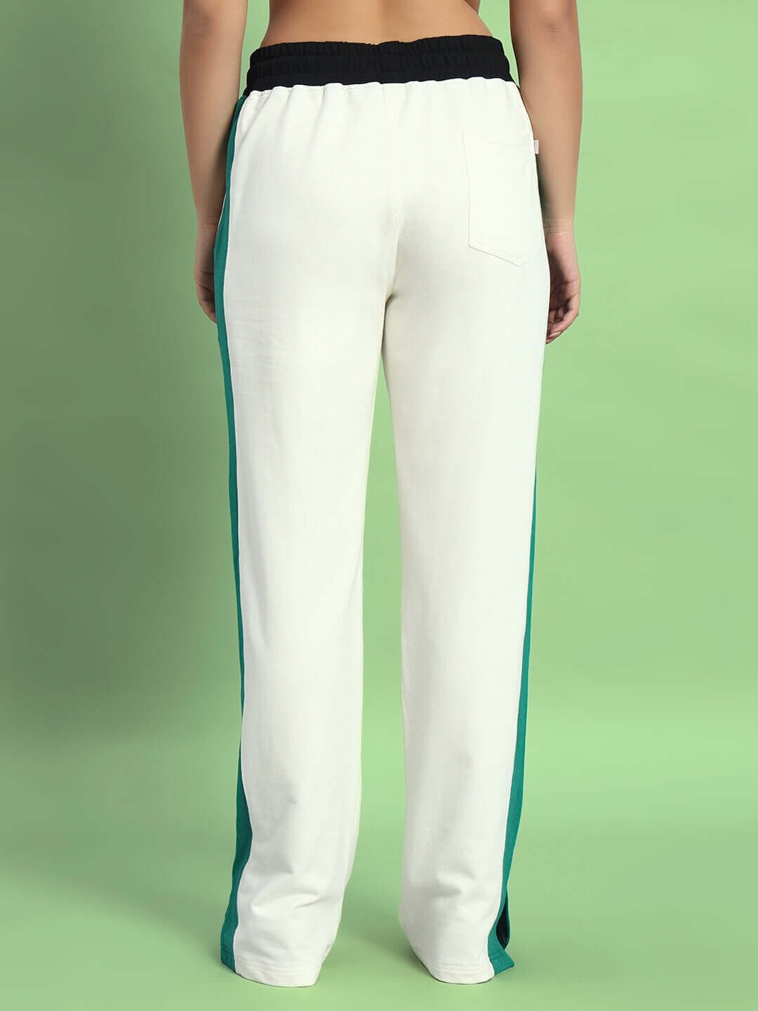 Back view of Women's Zingy Jogger pants in off white with teal side stripes, showcased on a green background.