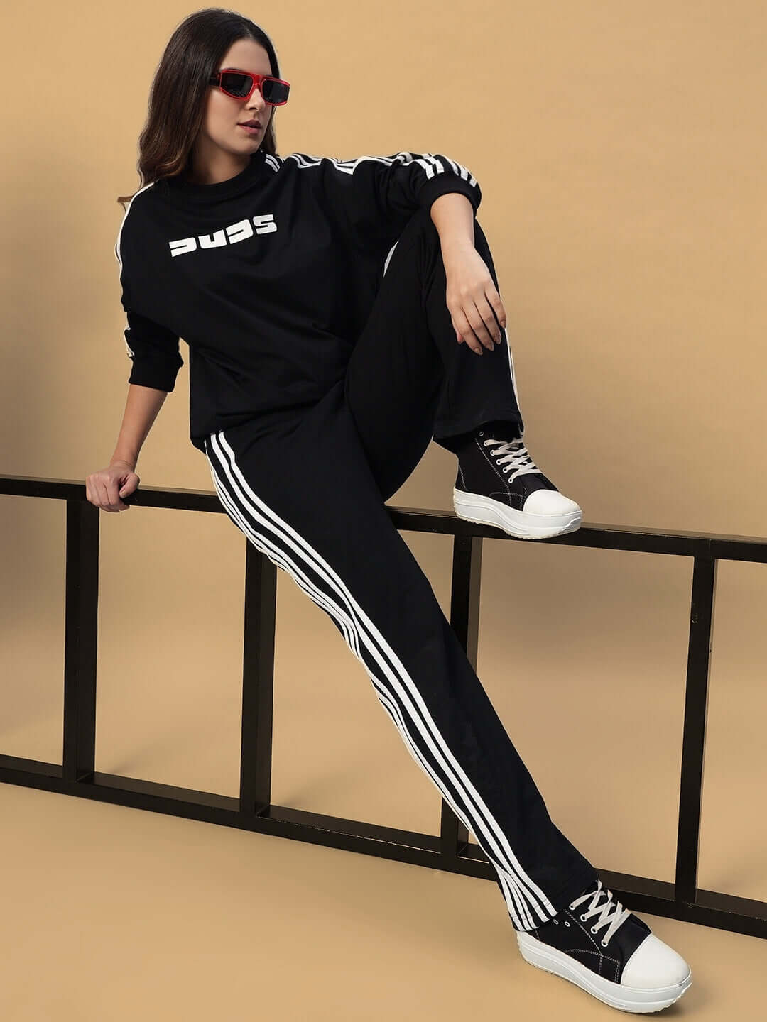 Model wearing black oversized parka co-ord set, featuring relaxed fit joggers with white stripes and sneakers, perfect for casual style.