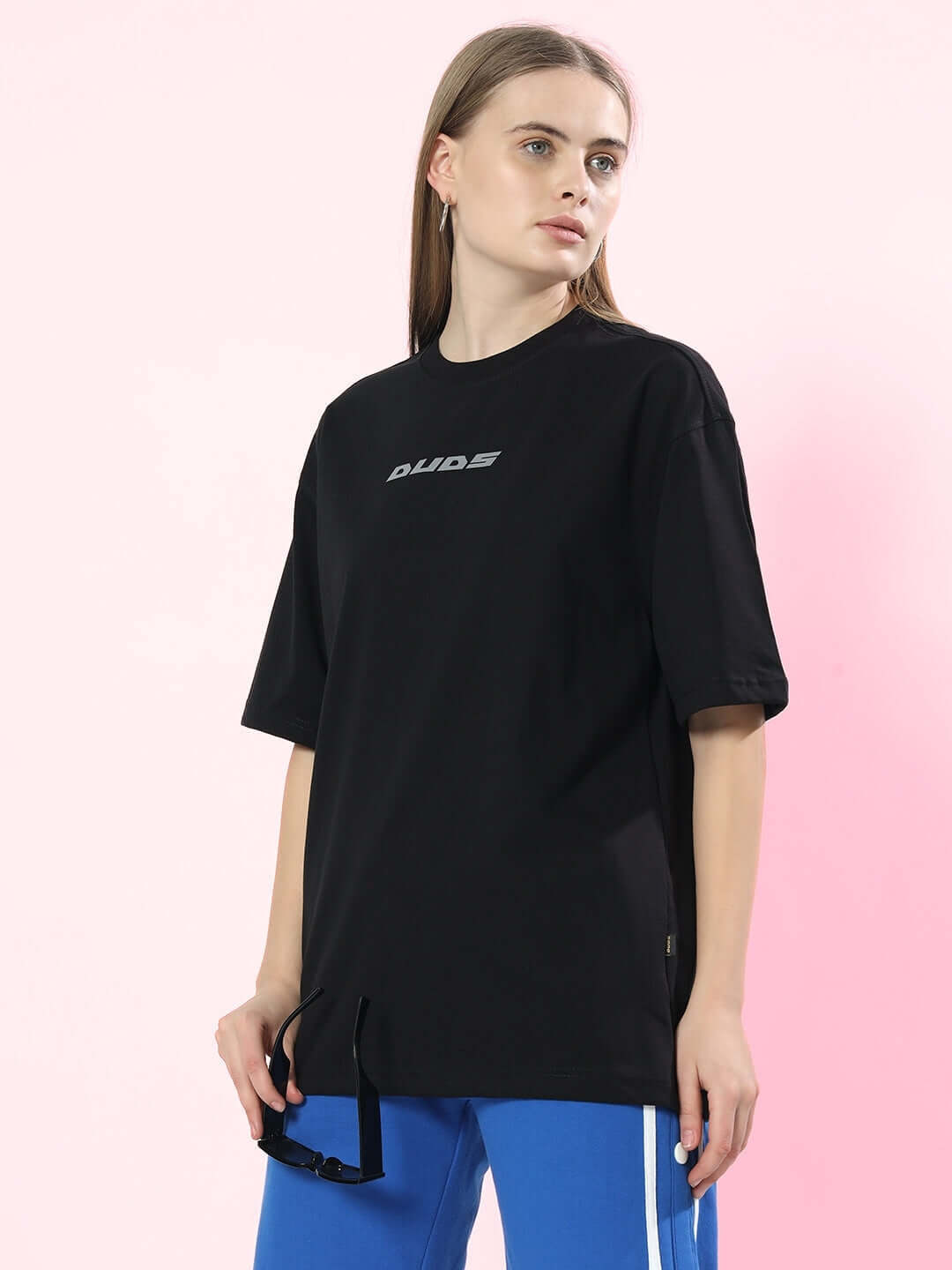 Model wearing women's oversized black t-shirt, premium cotton French terry, paired with blue pants, stylish casual outfit.