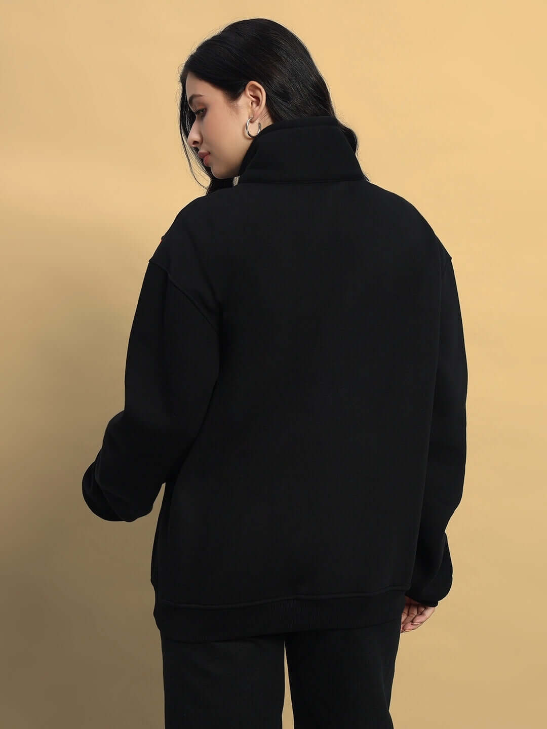 Woman wearing a black colorblock jacket, viewed from behind, featuring a cozy high collar and relaxed fit. Tailored by DUDS.