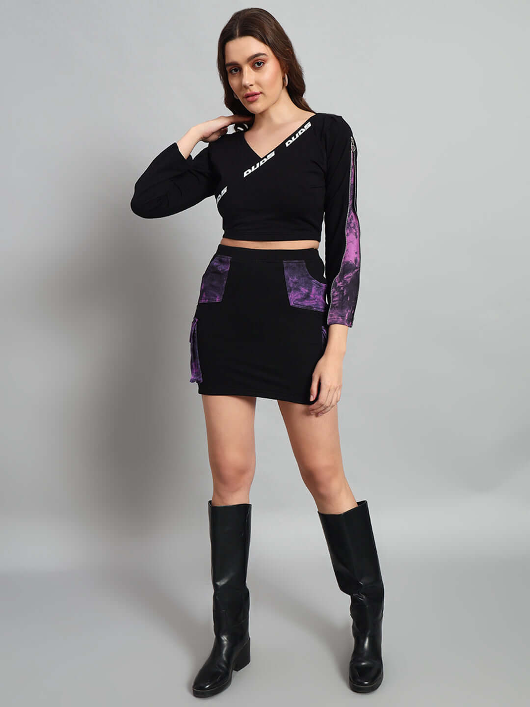 Woman wearing black-purple tie-dye crop top and skirt, made of premium cotton lycra. Fashionable outfit with black boots.
