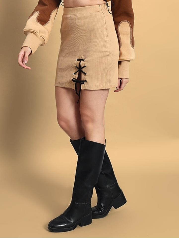 Model wearing the Women's Emma Co-ord Set in beige-brown, featuring a mini skirt with front lace detail and black knee-high boots.